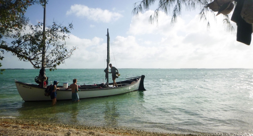 a sailboat rests near a beach on calm blue waters on an outward bound expedition in costa rica